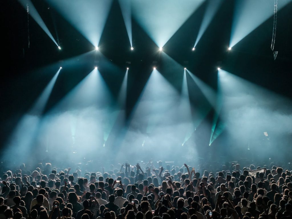 A dynamic concert scene with a large crowd enjoying vibrant stage lighting and a lively atmosphere.