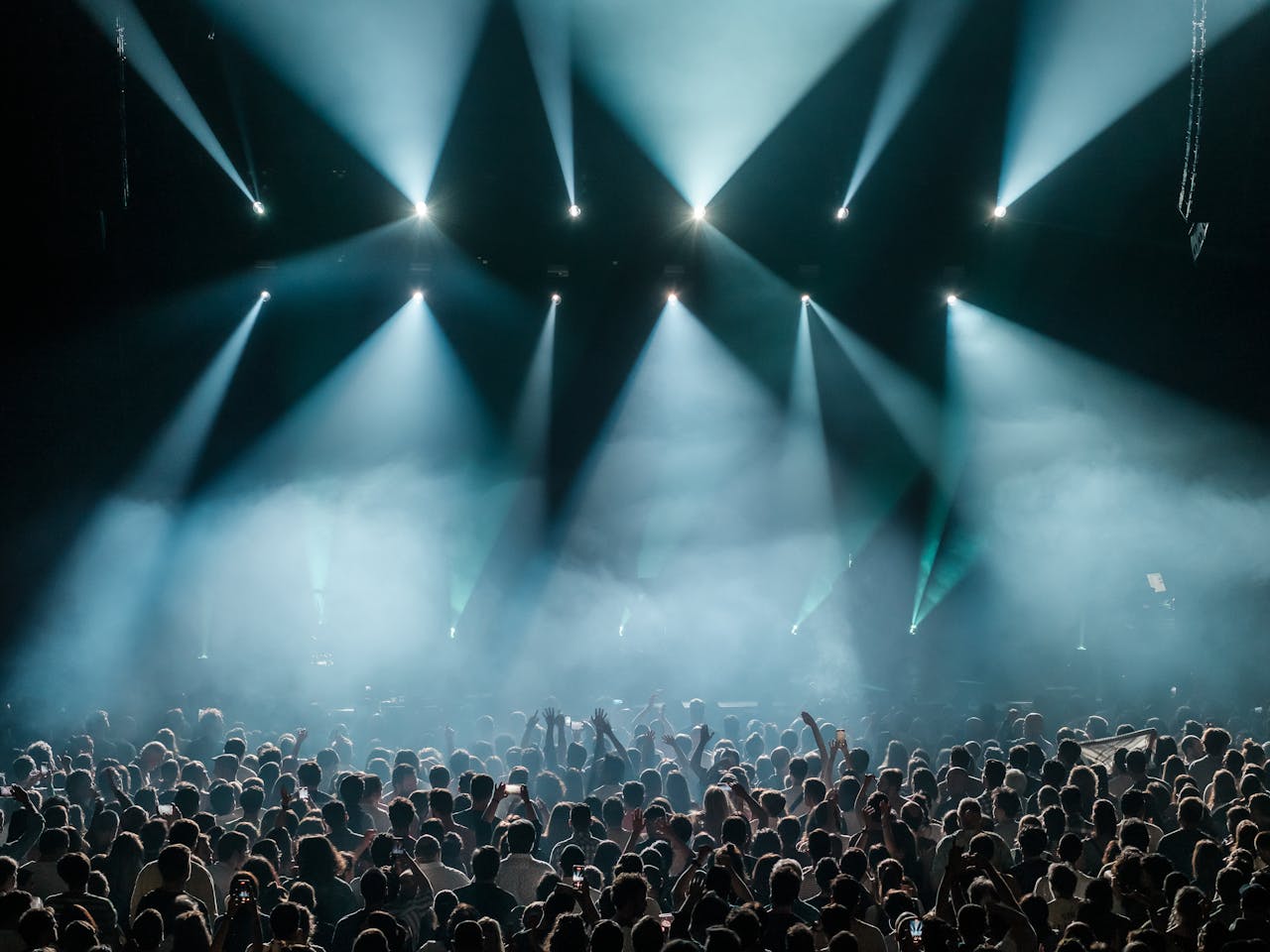 A dynamic concert scene with a large crowd enjoying vibrant stage lighting and a lively atmosphere.